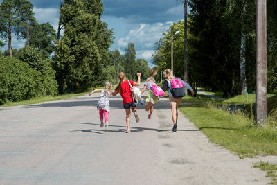 Children running on road against trees