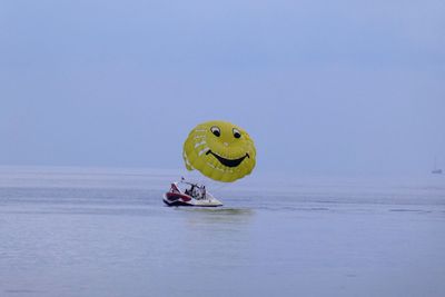 Person paragliding in sea against clear sky