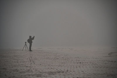 Silhouette people on beach against sky