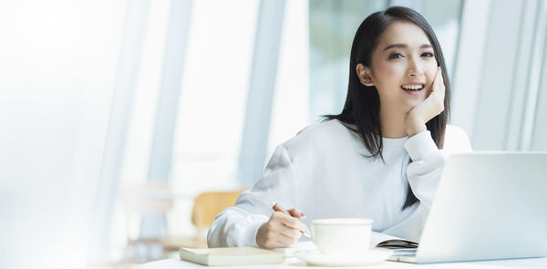 Portrait of young woman using smart phone on table