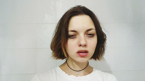 Portrait of young woman against wall