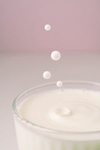 Milk drips into a transparent faceted glass.