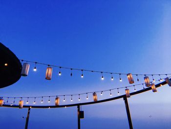 Low angle view of illuminated lights against clear blue sky