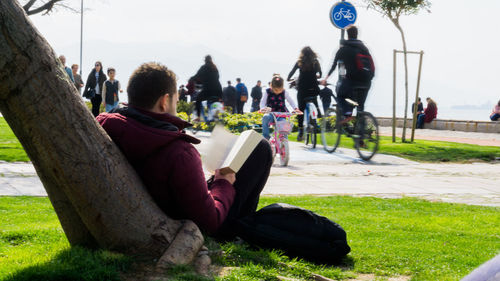 People sitting on grass against sky