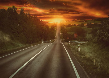 Road amidst trees against sky during sunset