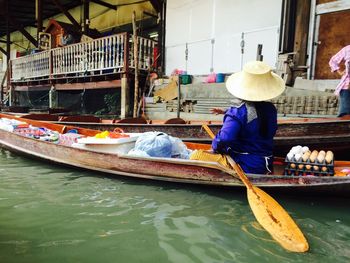 Woman selling eggs in boat on river