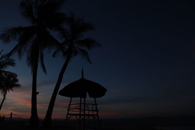 Silhouette coconut palm trees on beach against sky during sunset