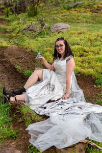 Young woman sitting on muddy road in wedding dress