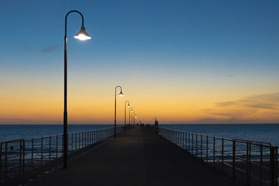 Pier over sea against sky during sunset