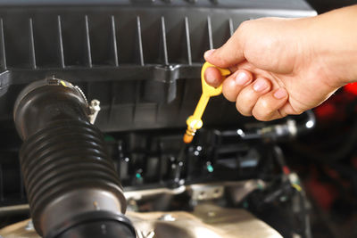 Car mechanic checking engine oil before leaving