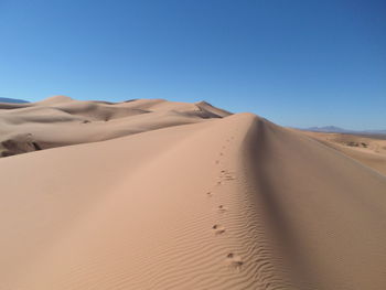 Sand dunes in desert against clear sky