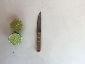 Close-up of halved citrus fruit by knife on white table