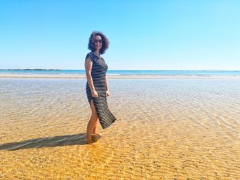 Portrait of woman standing at beach against sky