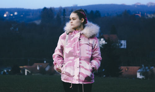 Young woman wearing warm clothing looking away on field