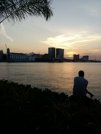 Rear view of silhouette of city at sunset