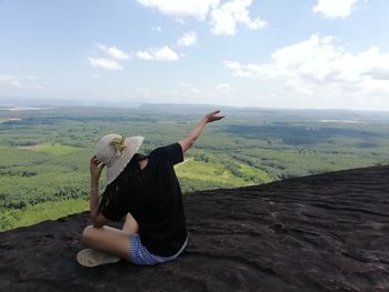 Full length of man sitting on land against sky