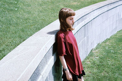 Young woman standing by retaining wall