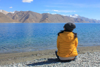 Rear view of woman looking at lake by mountain range