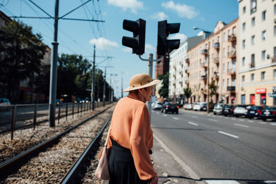 Man standing by railroad tracks against sky in city