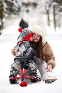 Son embracing with mother on snow covered land