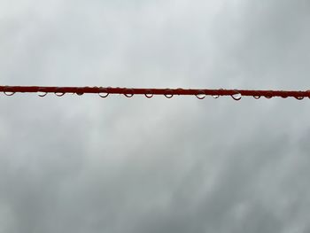 Low angle view of raindrops on metal against sky