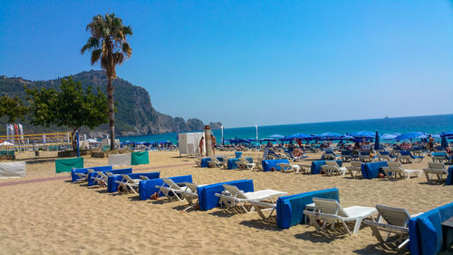 Chairs on beach against clear blue sky