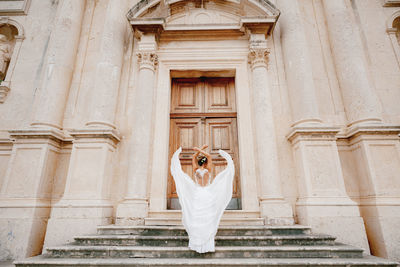 Full length of woman standing against building