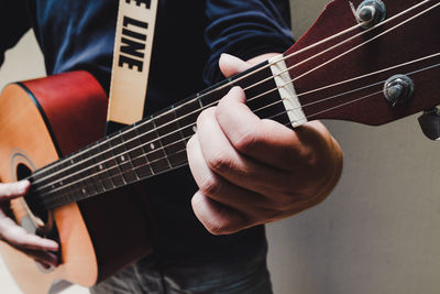 Midsection of man playing guitar