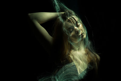 Digital composite image of young woman with light painting against black background