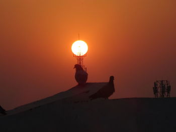 Silhouette person against orange sky during sunset