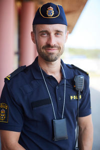 Portrait of smiling policeman in uniform standing outside police station