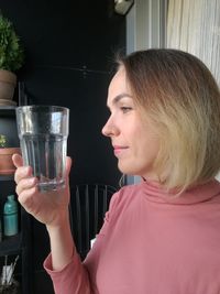 Close-up of woman holding water standing at balcony