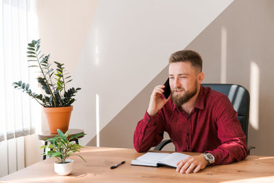 Business bearded man is talking on phone and plans to meet daily and write