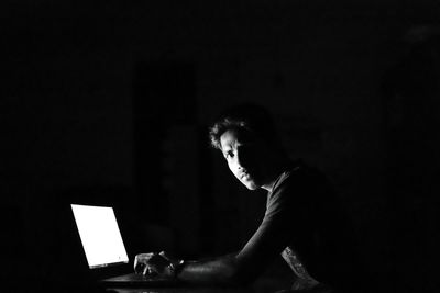 Young man using laptop against black background