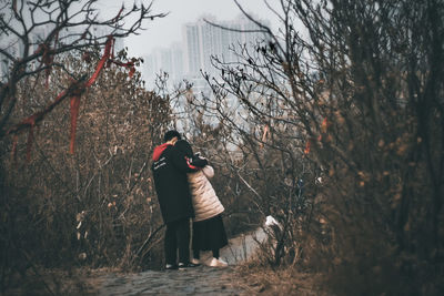 Man photographing woman standing in forest