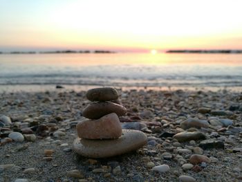 Close-up of pebbles on beach against sky during sunset