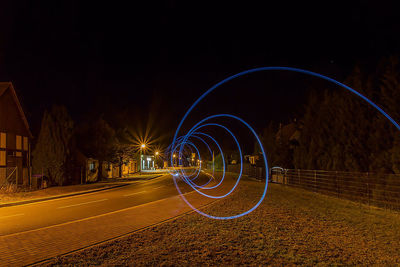 Light trails on road against sky at night