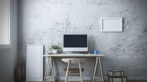 Empty chair and table against white wall