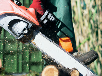 Low section of man sawing wood with chainsaw