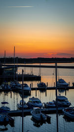 Boats moored at harbor during sunset