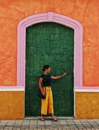Full length of woman standing against door of building