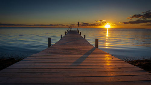 Pier over sea against sky during sunset