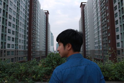 Portrait of man standing against buildings in city