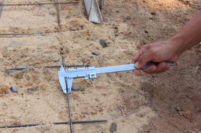 Cropped hand of man holding work tool on sand