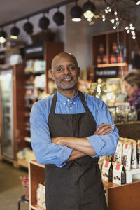 Portrait of confident owner standing with arms crossed at store