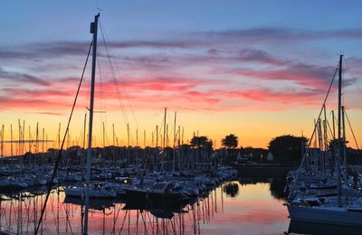 Boats moored at harbor during sunset