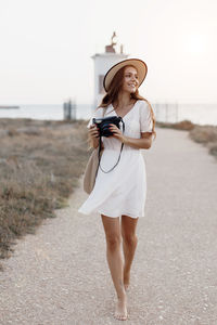 Full length of woman standing on beach against sky