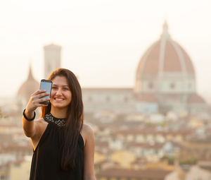 Young woman using smart phone against sky