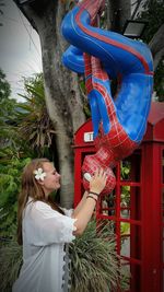 Side view of woman standing by palm tree