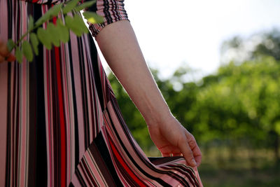 Midsection of woman holding umbrella standing outdoors